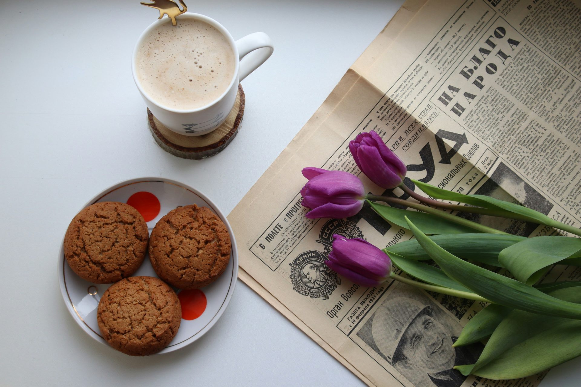 white ceramic mug with coffee beside purple flower